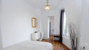 Un dormitorio con una cama grande, una mesita de noche, un espejo y una ventana con cortinas.