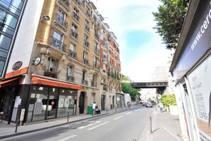A street view with a restaurant named "La Bauloise" on the left, a multi-story building with balconies, and a pedestrian walkway. - Appart Hameau Paris Porte de Versailles (Paris)