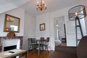 A dining area with a chandelier, a fireplace, and a dining table with chairs. - Appart Hameau Paris Porte de Versailles (Paris)
