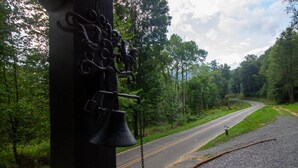 A road curving through a forest with a bell tower in the foreground.