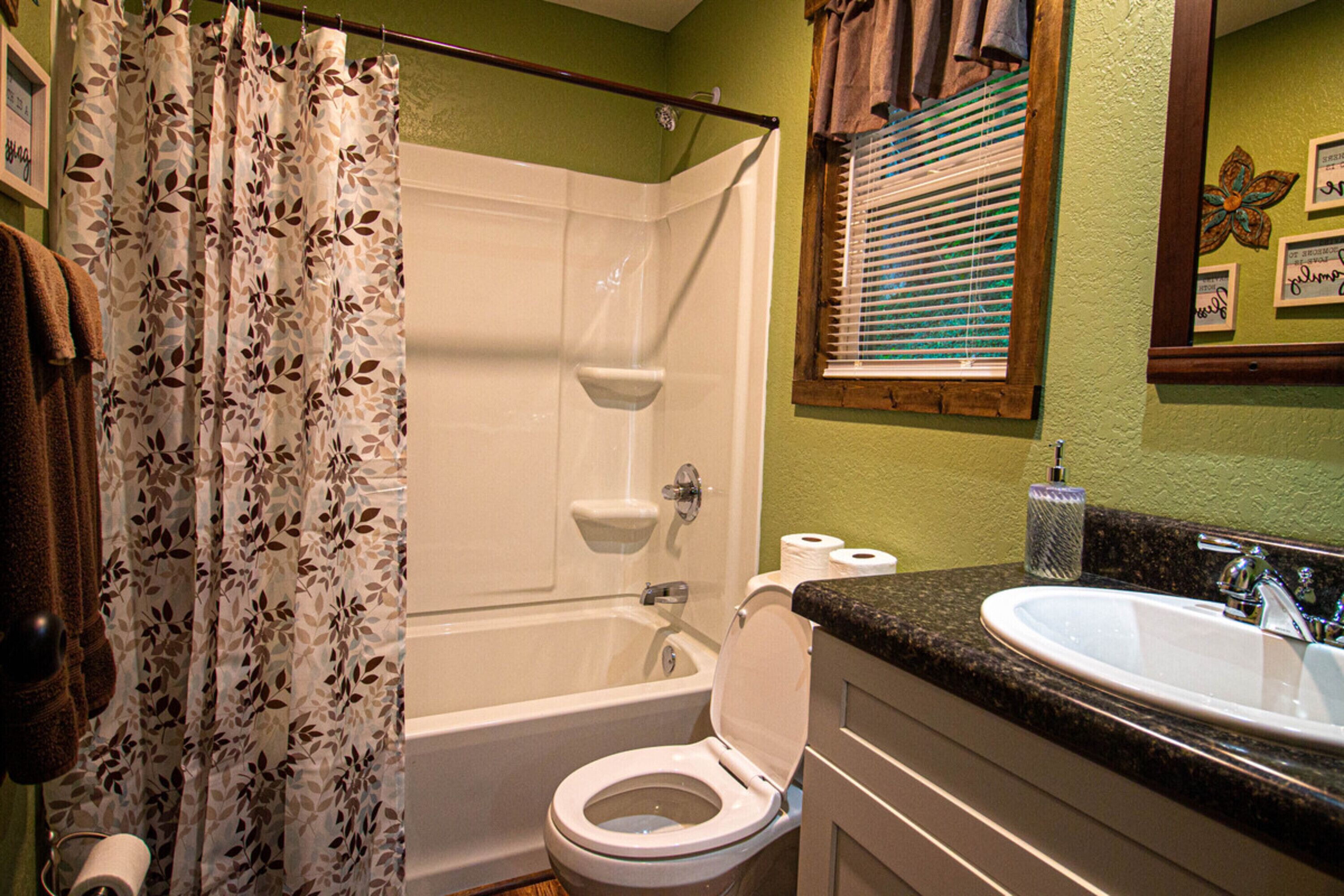 Une salle de bain équipée d’une douche, de toilettes, d’un lavabo et d’une fenêtre avec des stores.