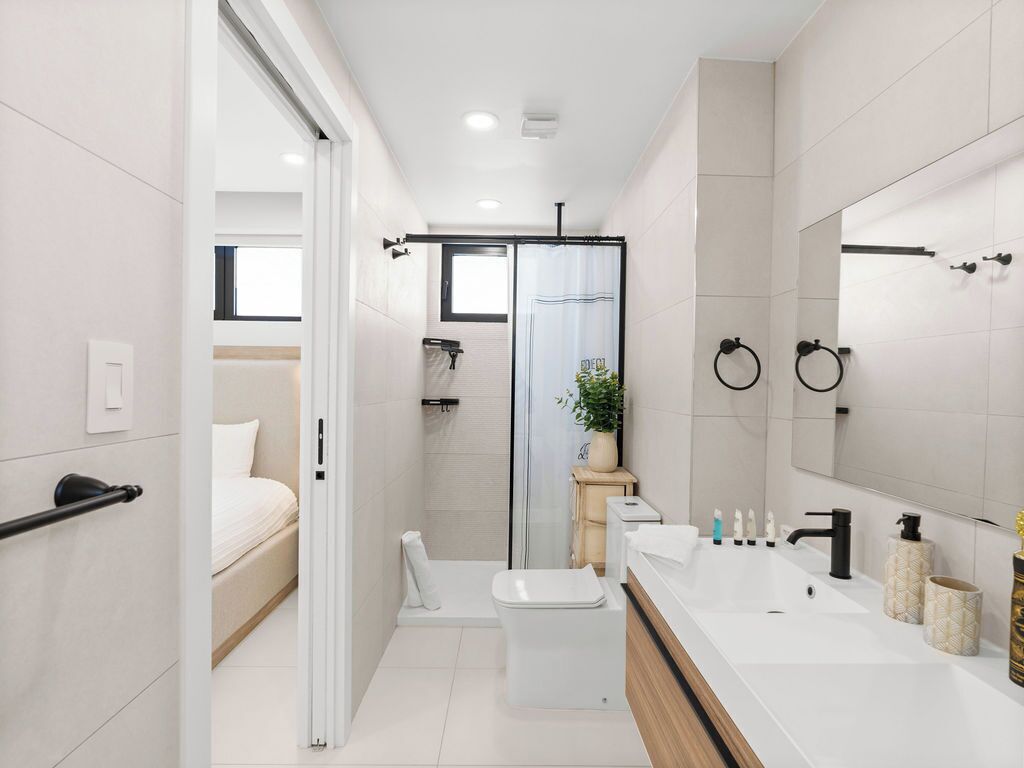 A modern bathroom with a shower, toilet, and a large mirror.