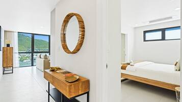 A modern hotel room with a large bed, a desk with a chair, a wooden wall decor, and a view of the outdoors.