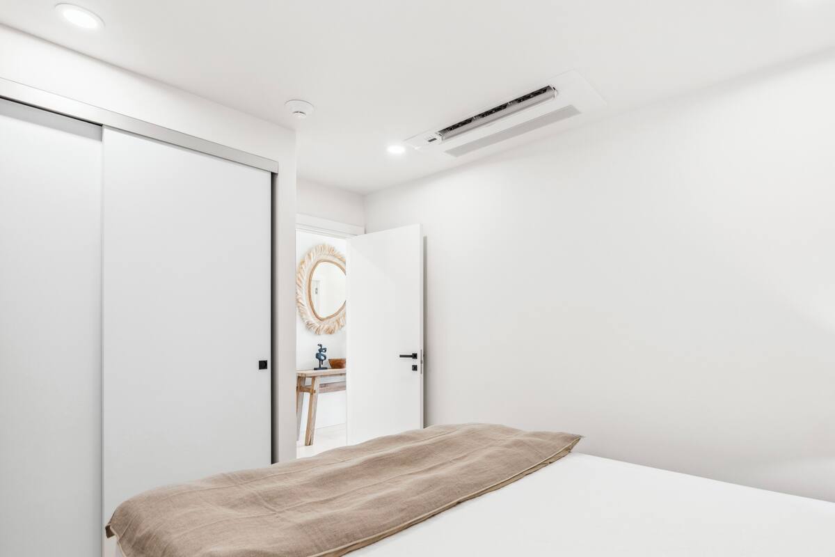 Ein Schlafzimmer mit einem Bett, einem Nachttisch, einem Spiegel und einem Kleiderschrank.