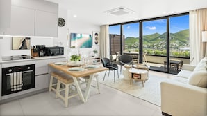 A modern kitchen with a dining area, a sofa, and a view of the mountains.