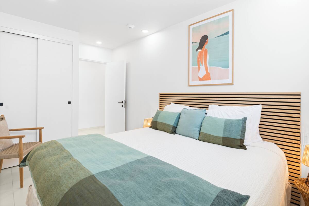Ein Schlafzimmer mit einem Bett, einem Sessel, einer Tür und einer Wand mit einem gerahmten Bild.