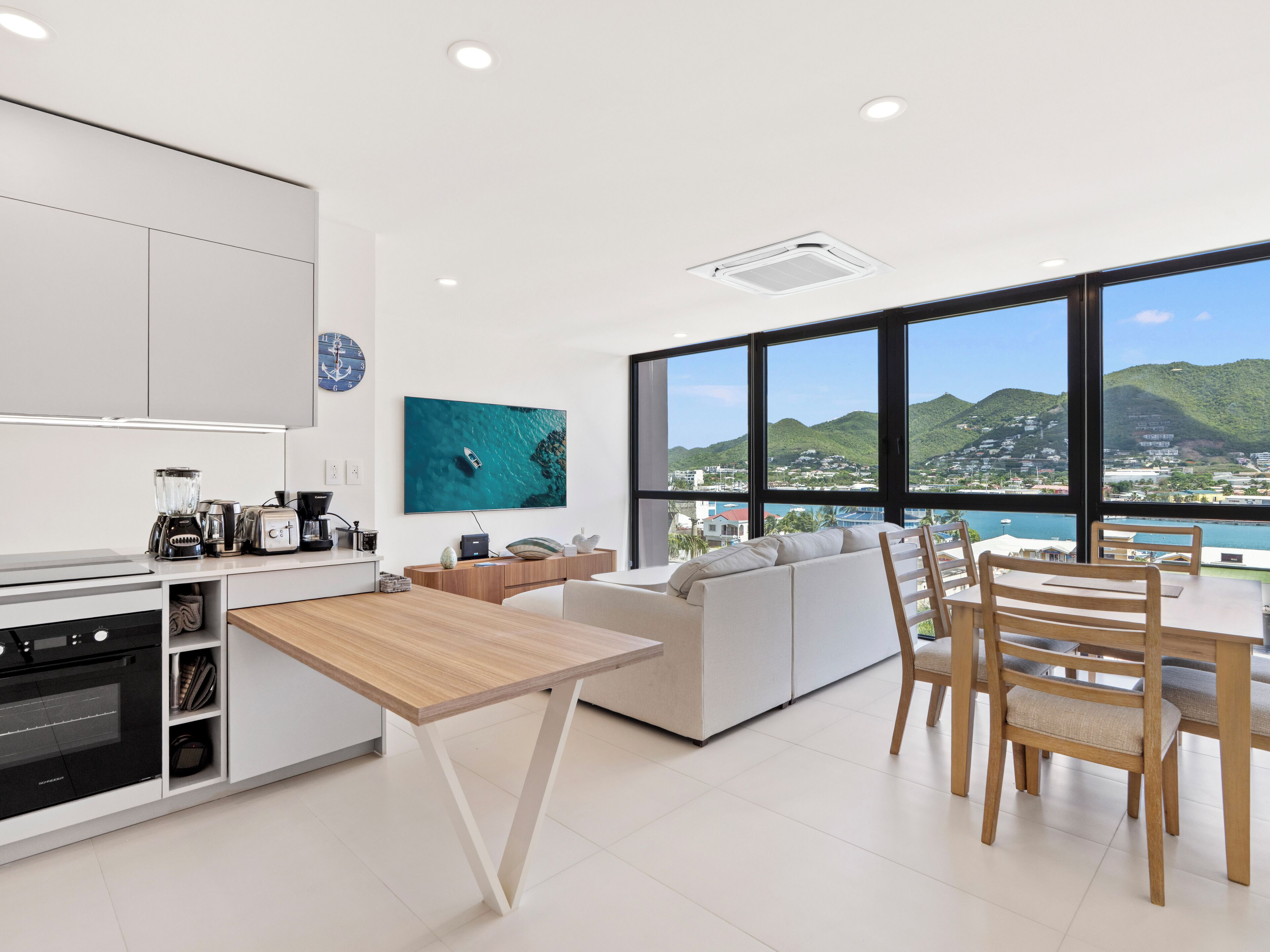 Una cocina moderna con comedor, amplios ventanales que ofrecen vistas a la ciudad y las colinas.