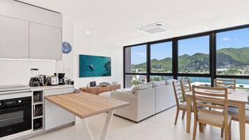 Una cocina moderna con comedor, amplios ventanales que ofrecen vistas a la ciudad y las colinas.