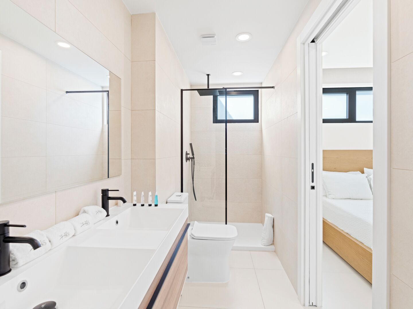 A modern bathroom with a large mirror, a bathtub, a toilet, and a shower area.
