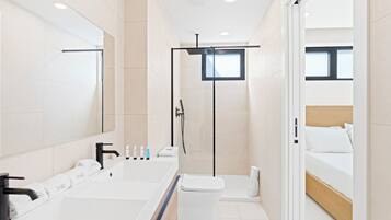A modern bathroom with a large mirror, a bathtub, a toilet, and a shower area.