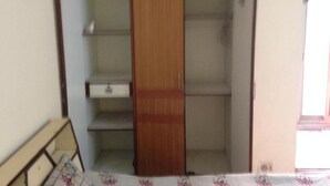 Een kamer met een houten garderobe, een klein tafeltje en een tafelkleed met bloemenprint.