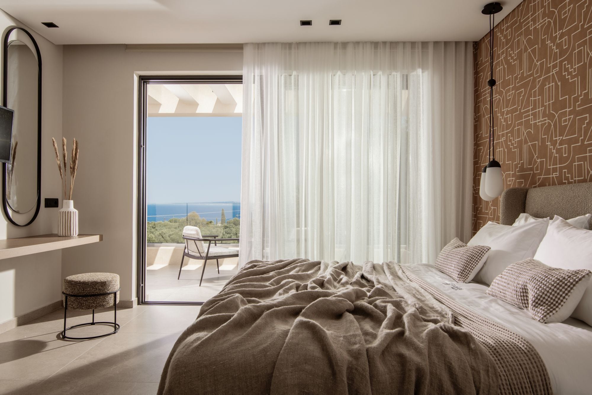 A modern bedroom with a large bed, a view through a glass door, a small balcony, and a patterned wall.