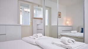 Hotellihuone, jossa on sänky, peili ja ikkuna.