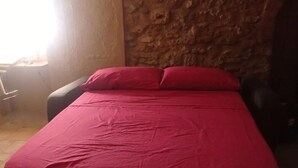 A room with a bed, a stone wall, and a window with sunlight. - Historical center casale (Casale Marittimo)