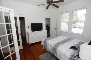 Relax in this stylish bedroom with a comfortable bed, TV, and ceiling fan.