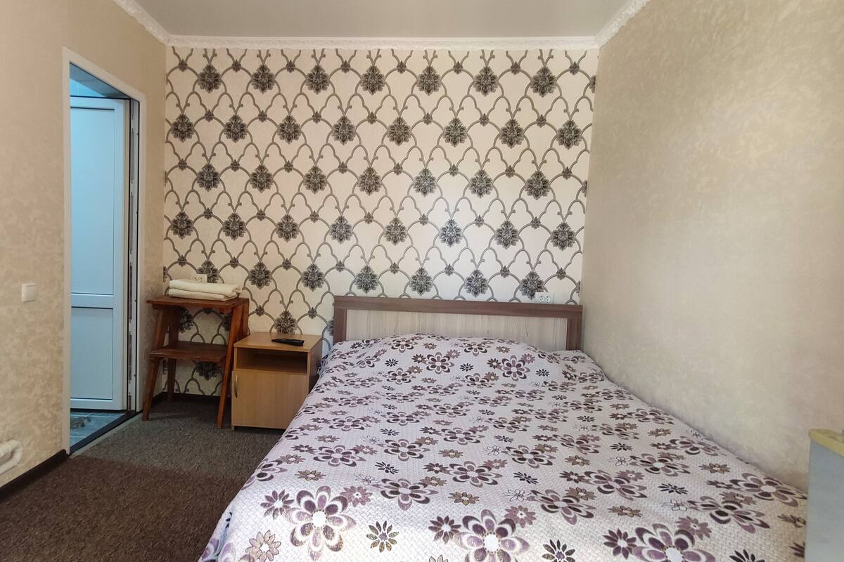 A bedroom with a bed, a desk, and a chair.