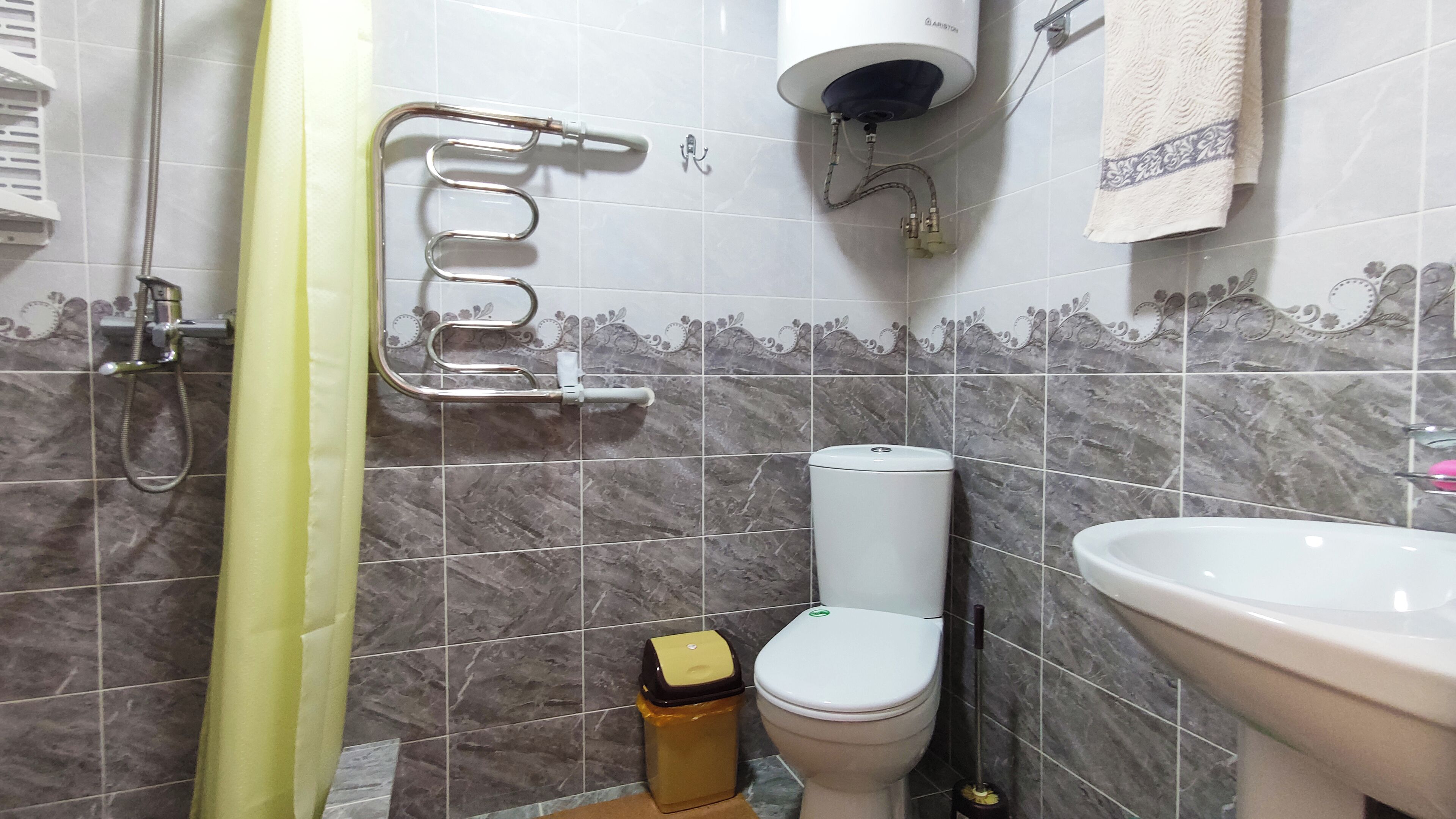 Un baño con inodoro, lavamanos, ducha y toallero.