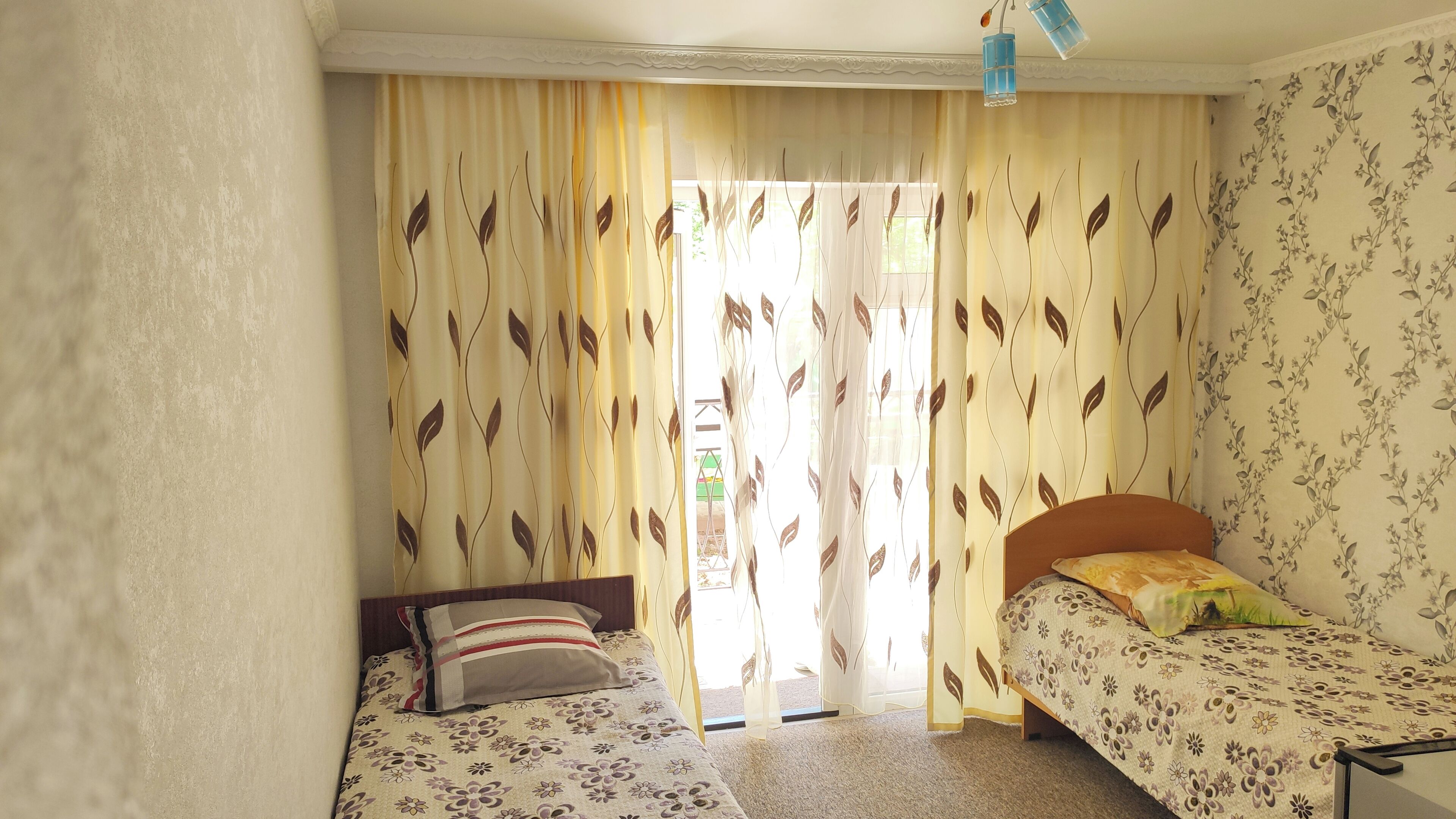 A room with two beds, a window with curtains, and a door.