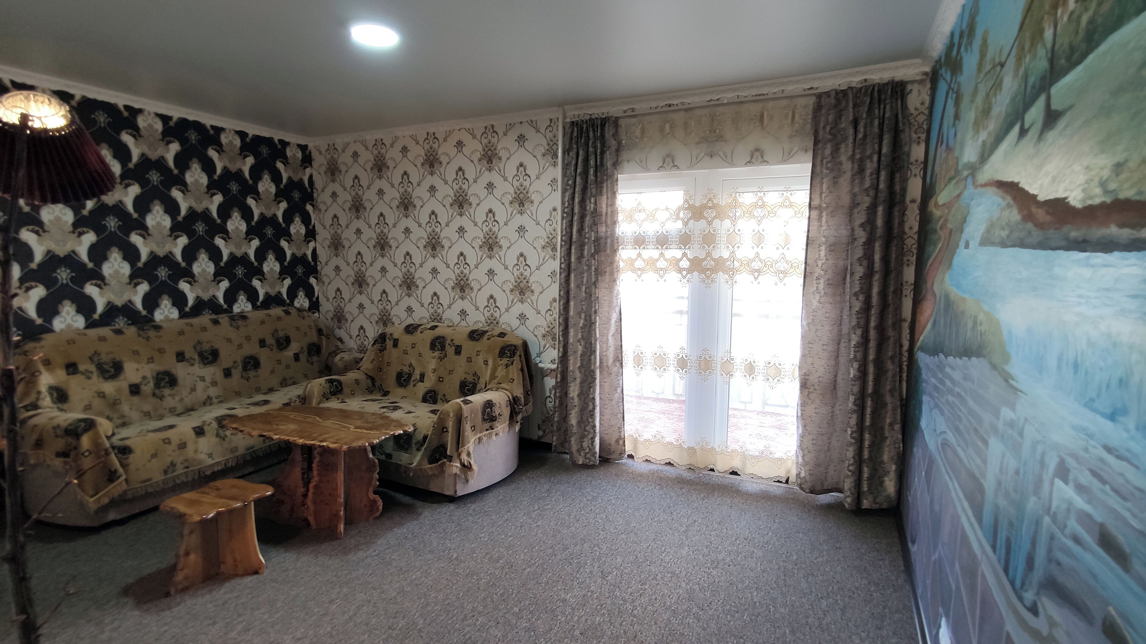 Una sala de estar con papel tapiz estampado, un sofá, una mesa de centro y un cuadro en la pared.