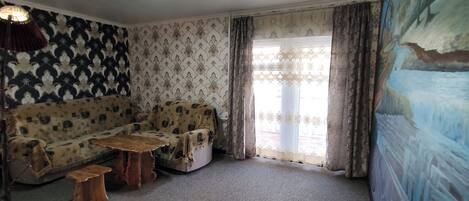 Una sala de estar con papel tapiz estampado, un sofá, una mesa de centro y un cuadro en la pared.
