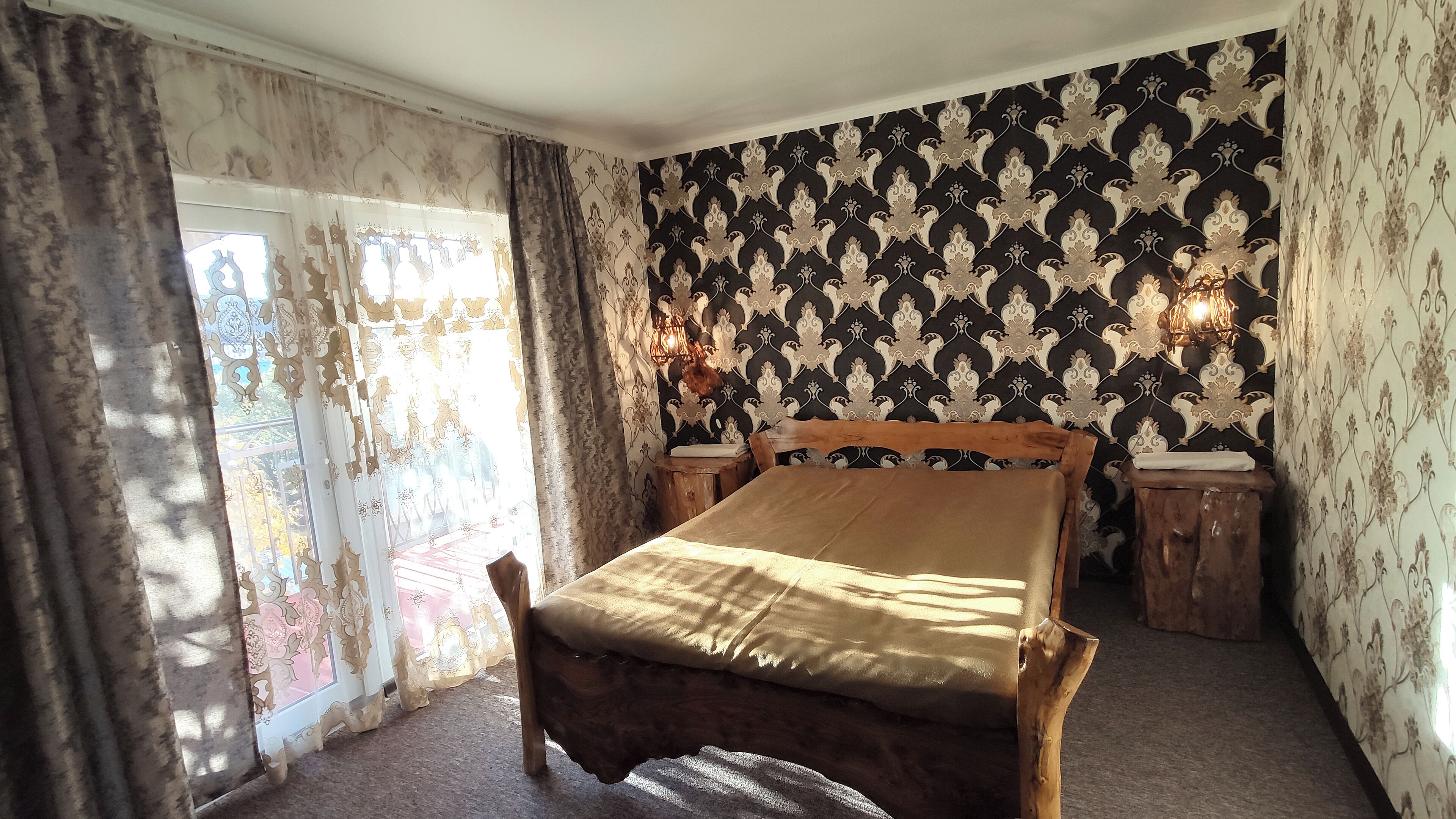 A bedroom with a wooden bed, patterned wallpaper, and a window with curtains.