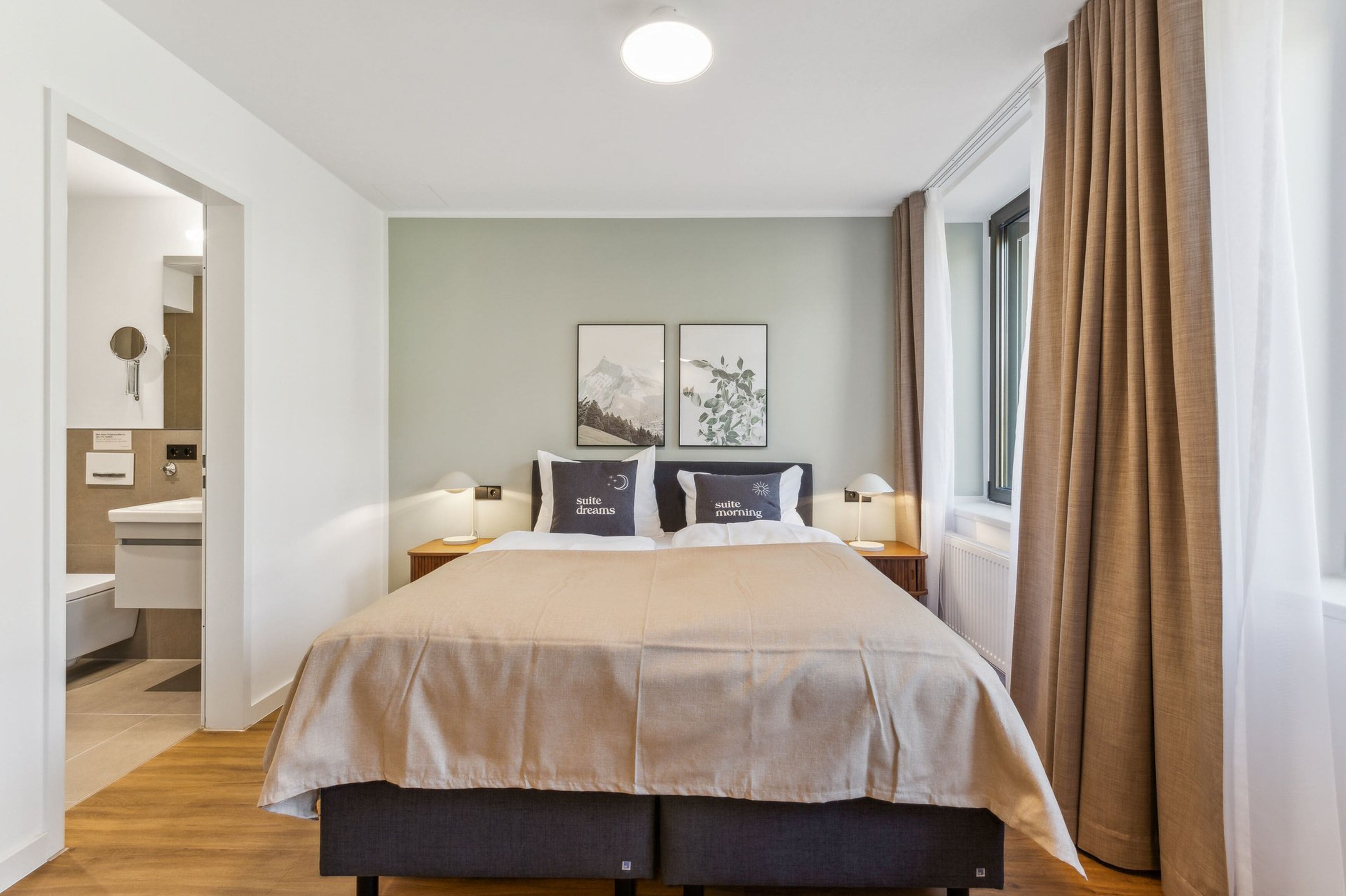 A modern bedroom with a large bed, bedside lamps, and a window with curtains.
