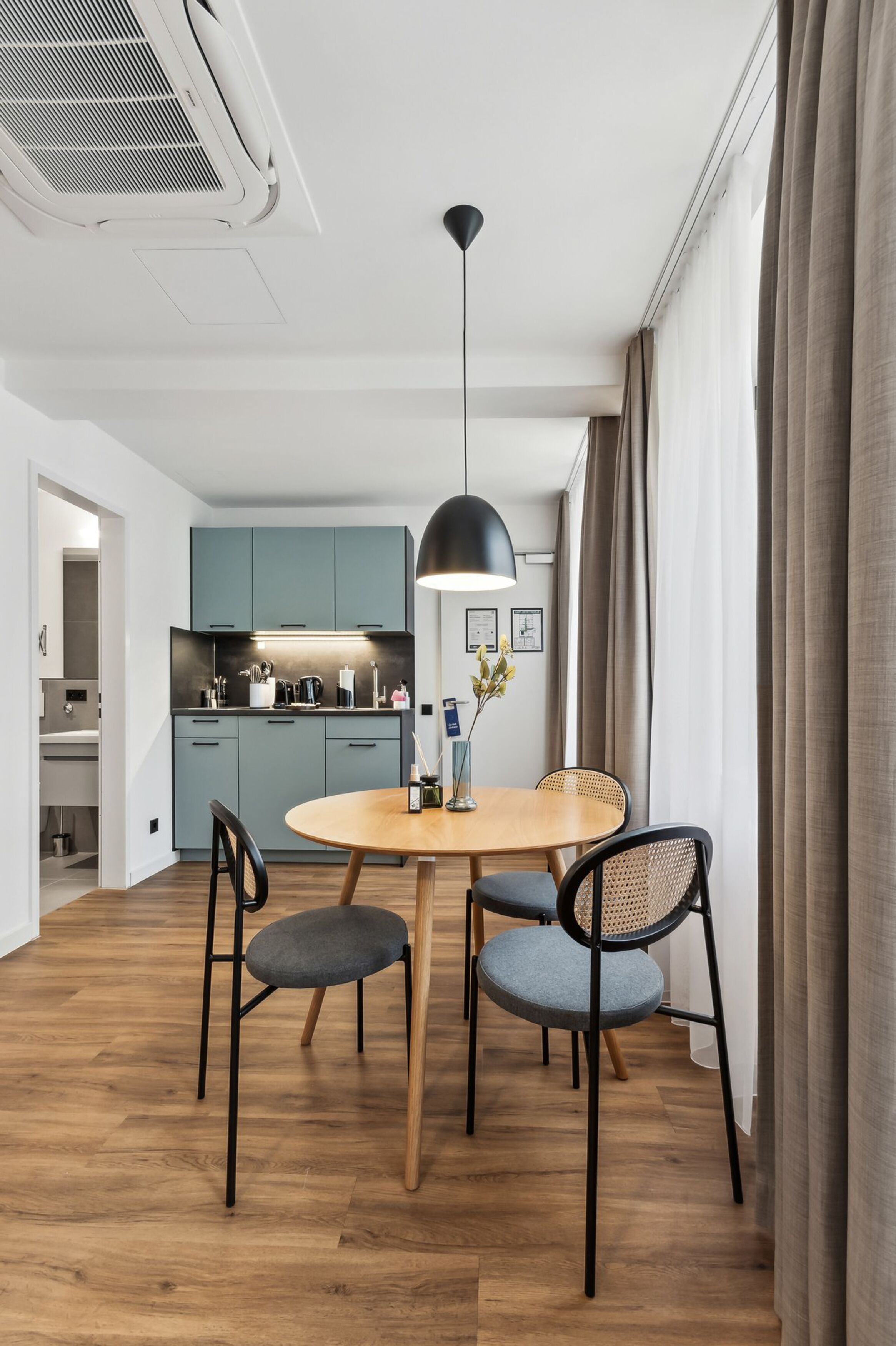 A modern kitchen with light blue cabinets, a round wooden table, and two chairs.