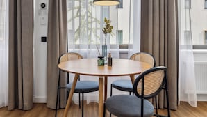 A dining area with a round table, four chairs, a black pendant light, and a window with sheer curtains. - Limehome Oberhausen Paul-Reusch-Str. (Oberhausen)