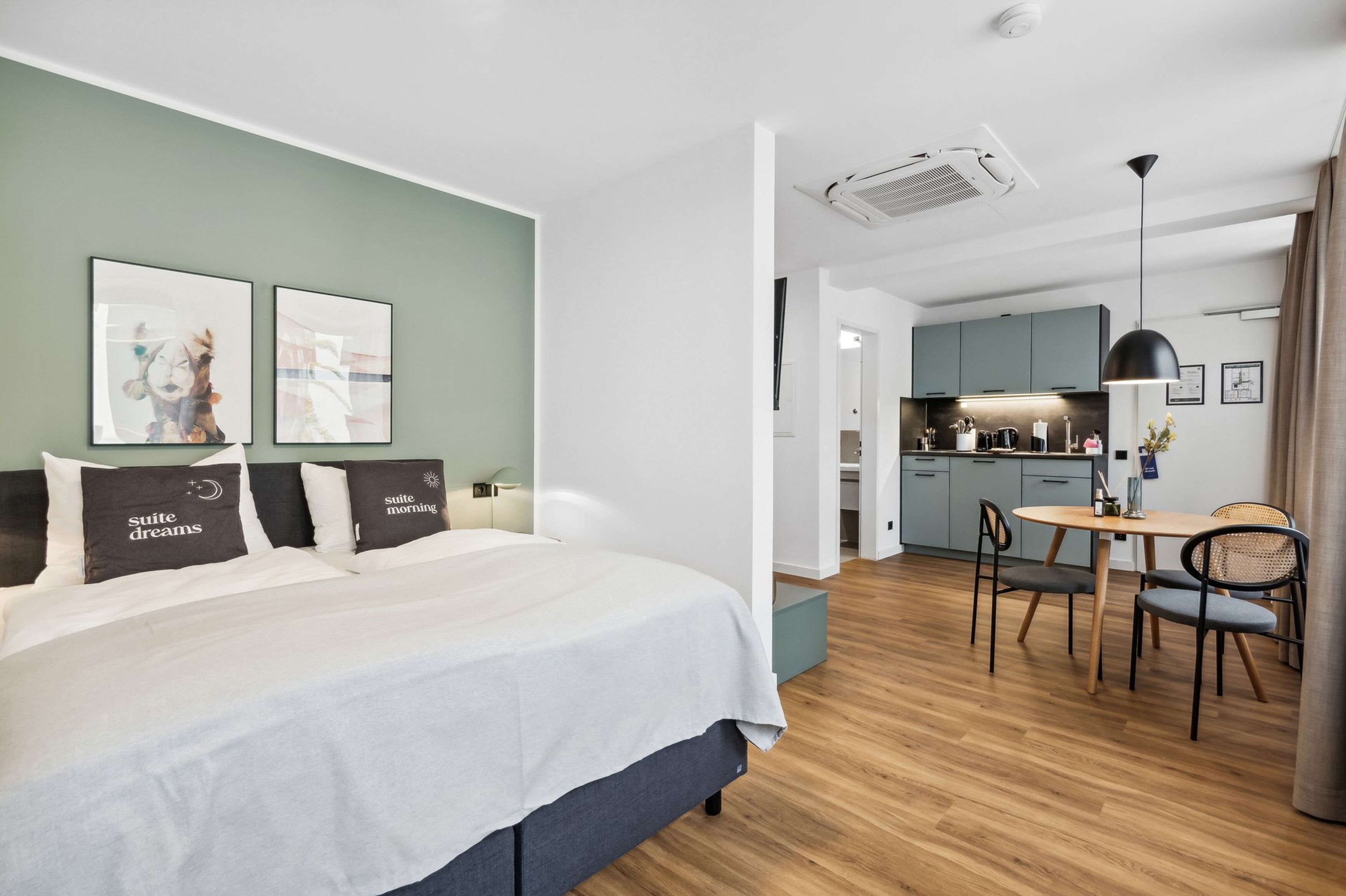 Una habitación de hotel moderna con cama, una pequeña zona de comedor y una kitchenette.