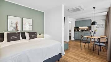 Una habitación de hotel moderna con cama, una pequeña zona de comedor y una kitchenette.