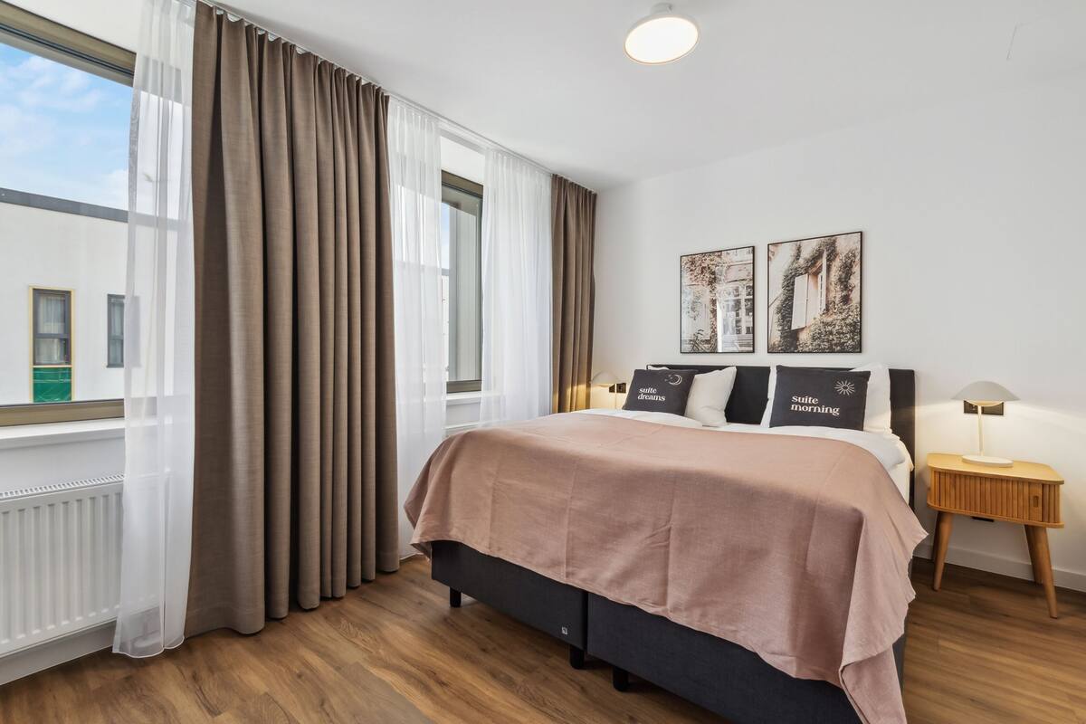 A modern bedroom with a large bed, a nightstand, and two wall-mounted lamps.