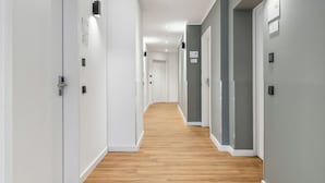 A long, narrow hallway with wooden flooring and white walls. - Limehome Oberhausen Paul-Reusch-Str. (Oberhausen)