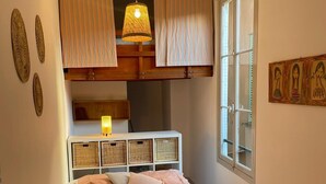 Un dormitorio con cama, ventana y lámpara colgante.