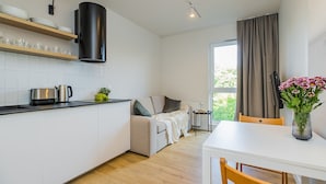 Eine moderne Küche mit weißen Schränken, einer schwarzen Dunstabzugshaube und einem Essbereich mit einem weißen Tisch und Holzstühlen.