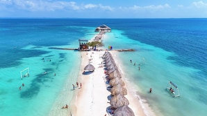 A beach resort with a long pier leading to overwater bungalows, clear turquoise waters, and a sandy beach. - Hotel oasis tolu boutique  (Tolú)