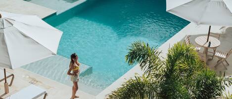 A pool area with lounge chairs, a small dog, and a person in swimwear.