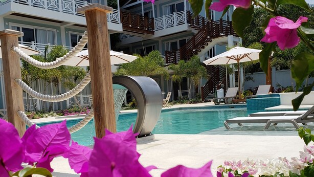 A pool area with lounge chairs and umbrellas, surrounded by bougainvillea flowers.
