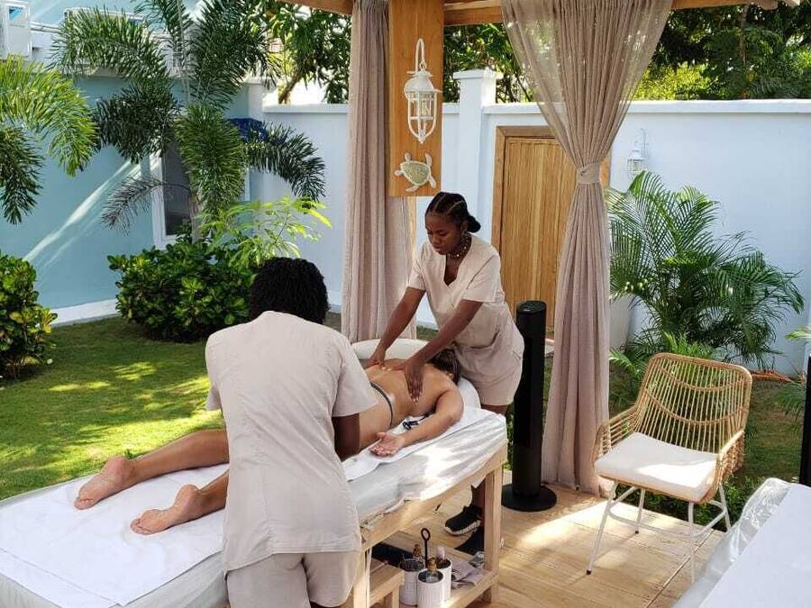 A massage therapy session in a wooden outdoor setting with a pergola, a massage table, and a chair.