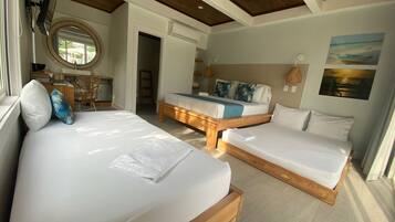 Une chambre d’hôtel avec deux lits, un plafond en bois, un miroir rond et une décoration murale sur le thème de la plage.