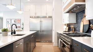 A modern kitchen with stainless steel appliances, a central island, and pendant lighting. - Desert Mirage: Private Pool, Foosball, Putting Green, Wheelchair Access (Hurricane)