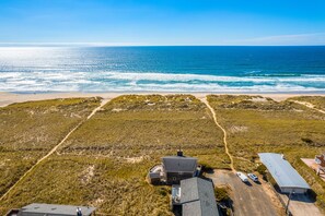 An aerial view of a coastal property with a beach, grassy dunes, and a large building with a flat roof. - Pet and Family Friendly-Just Steps From the Ocean (Manzanita)