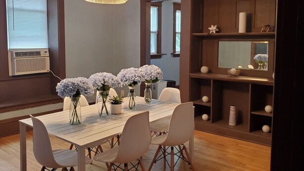 A dining area with a wooden table, white chairs, and floral centerpieces. - Ana Maria del Azul DT Minneapolis US Bank Stadium (Minneapolis)