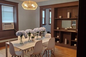 Un espace repas avec une table en bois, des chaises blanches et des centres de table ornés de motifs floraux.