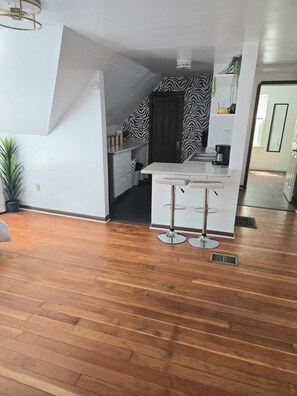 A modern kitchen with white cabinets, a zebra-patterned wall, a coffee machine, and a bar stool. - Ana Maria del Azul DT Minneapolis US Bank Stadium (Minneapolis)