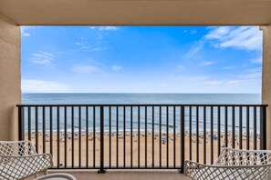 A balcony with a view of a beach and the sea.