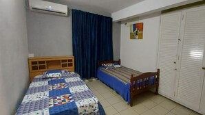 A bedroom with two single beds, a wardrobe, and an air conditioning unit. - Bungalow Front de mer 7 (Blue Bay)
