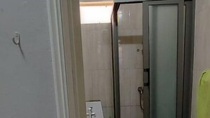 A bathroom with a toilet, a shower area, and a tiled floor. - Bungalow Front de mer 7 (Blue Bay)