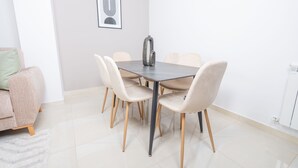 Un comedor con una mesa redonda, seis sillas y un jarrón decorativo.