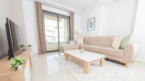 Una sala moderna con sofá, una mesa de centro, televisión y vistas a través de un ventanal corredero.