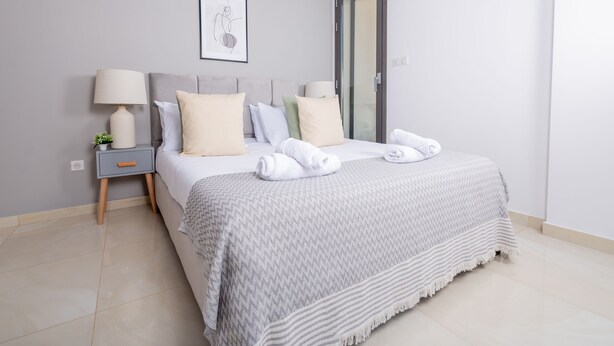 Un dormitorio ordenado con cama, mesitas de noche y una puerta.